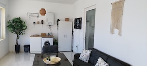 Un espace de vie moderne comprenant un canapé, une table à manger, un lave-linge, un radiateur et une plante.