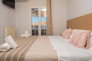 Ein Hotelzimmer mit Bett, Heizkörper, Fernseher und Fenster mit Blick auf Gebäude.