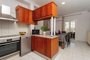 Eine Küche mit Mikrowelle, Backofen, Holzausstattung, Spüle und einem Essbereich mit Stühlen.