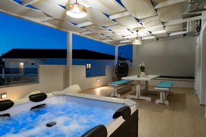 Ein moderner Außenbereich mit Whirlpool, Sitzgelegenheiten, einem Tisch und einer Hängematte.