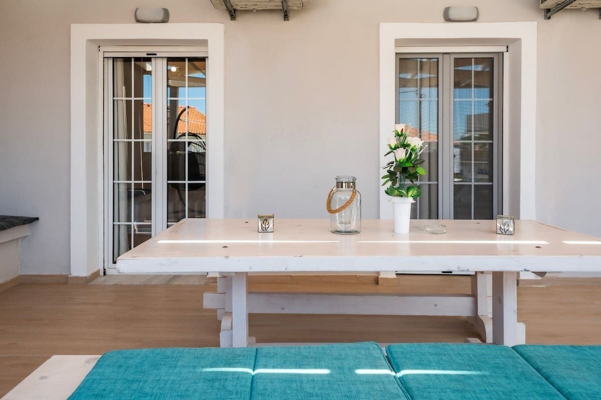 Une pièce avec une table blanche, deux chaises, une plante et un vase.