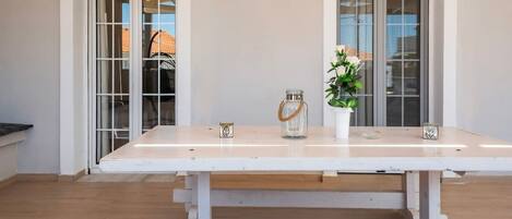 Une pièce avec une table blanche, deux chaises, une plante et un vase.
