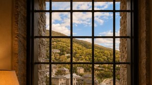 A window with a grid pattern, a candle, and a vase on the windowsill. - Monopatia Resort (Zagori)