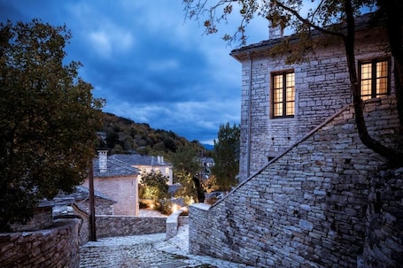 A stone building with a staircase, a window, and a tree.