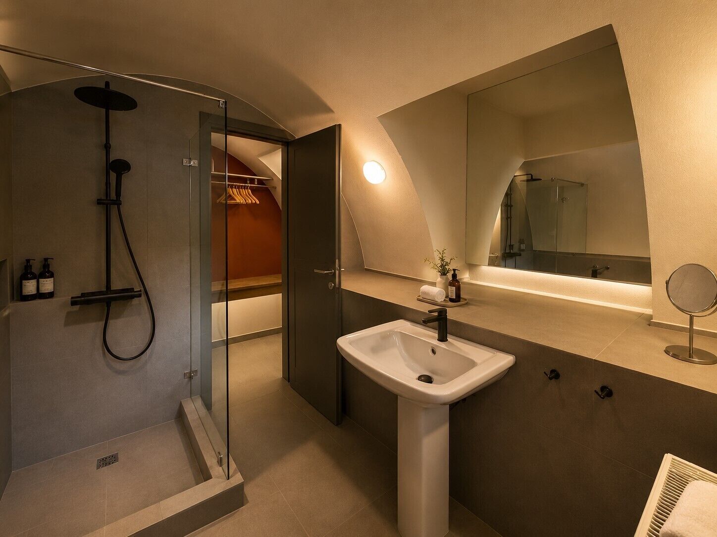 A modern bathroom with a shower, sink, and mirror.