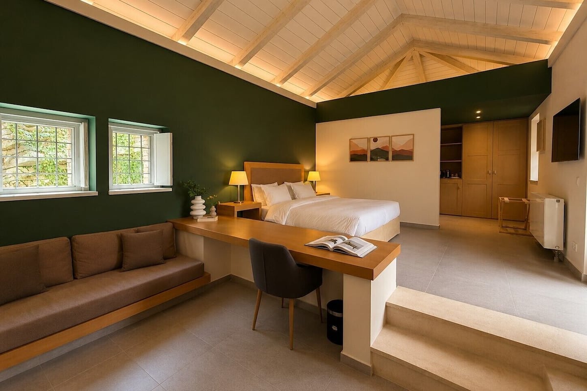 Un dormitorio con cama, mesitas de noche, escritorio, silla, sofá y una escalera.