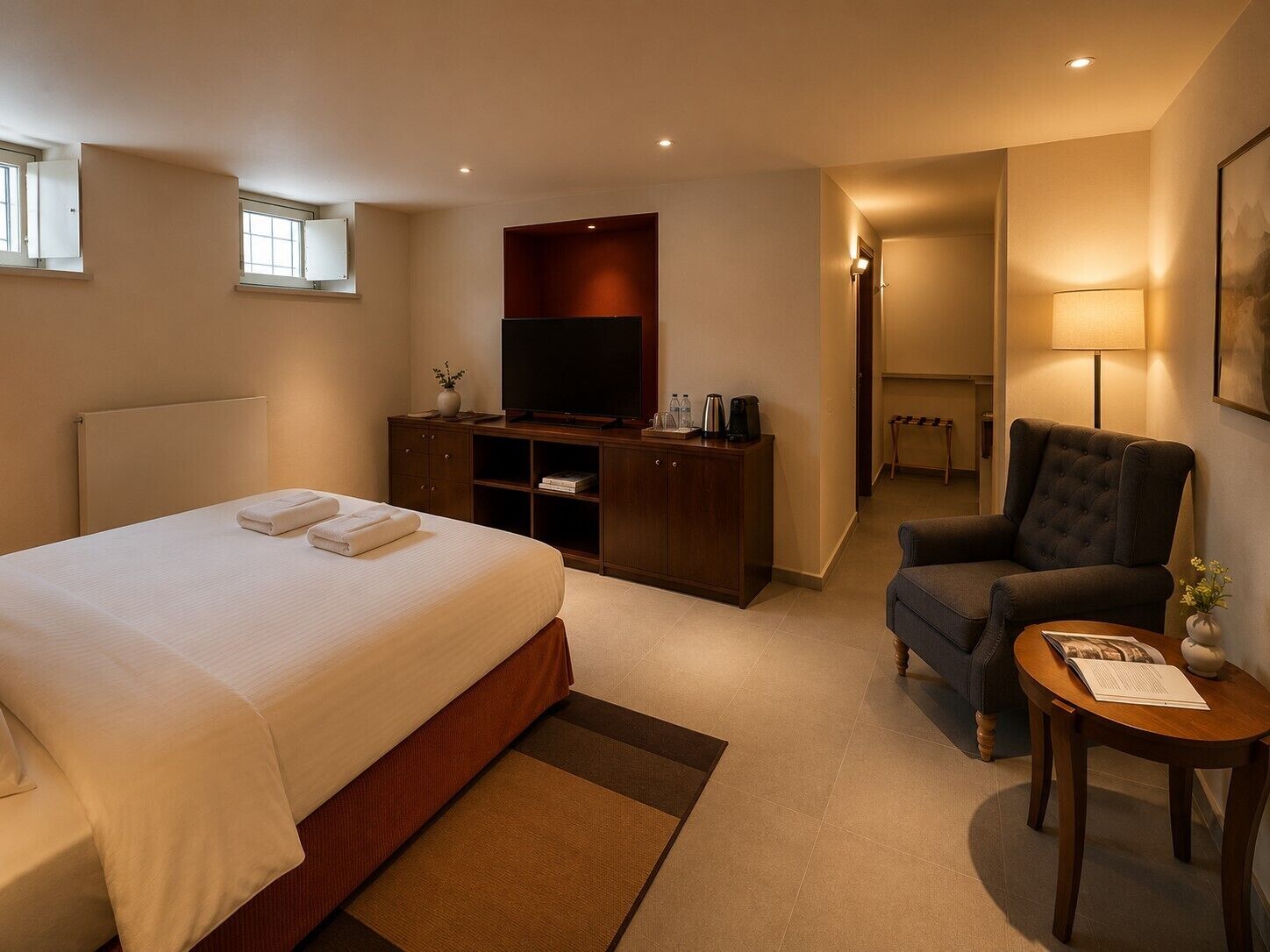 Ein Hotelzimmer mit Bett, Fernseher, Schreibtisch und Stuhl.