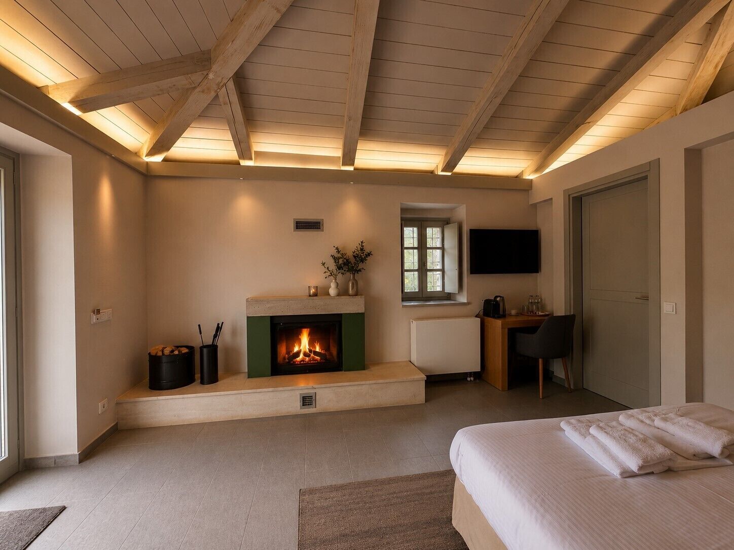 Une chambre avec une cheminée, un lit, un bureau et un téléviseur.