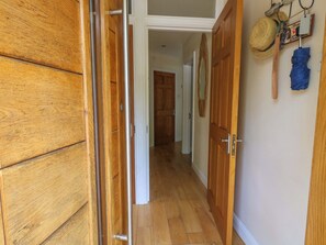 Ein Korridor mit Holztüren, Holzboden und einem Hut an der Wand.