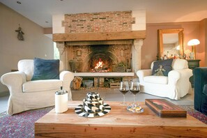 Ein Wohnzimmer mit Kamin aus Ziegelsteinen, weißen Sofas, einem Couchtisch mit Dekoration und einem Spiegel an der Wand.