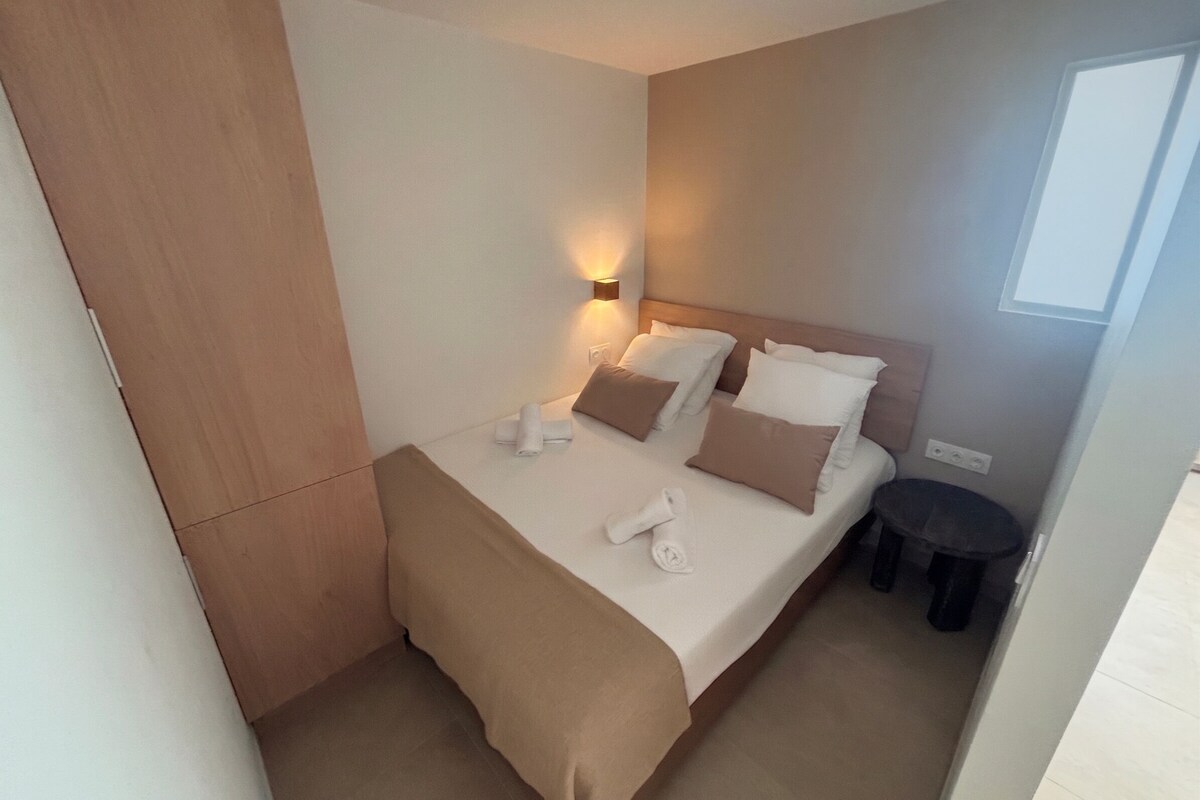 Quarto de hotel com cama, mesa de cabeceira e uma pequena mesa redonda.