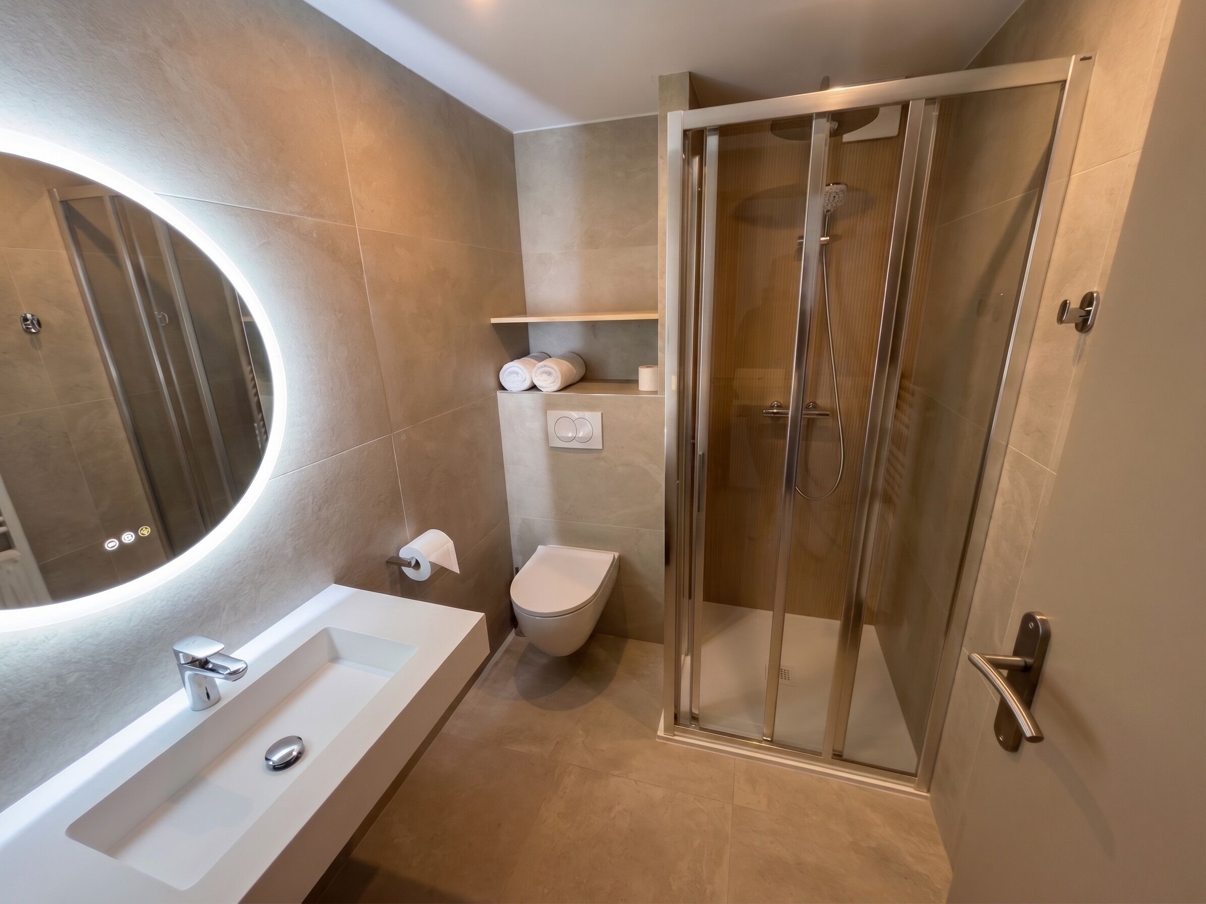 A modern bathroom with a glass-enclosed shower, a white sink, and a toilet.