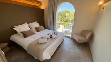 A bedroom with a large bed, a chair, and a view of the outdoors.