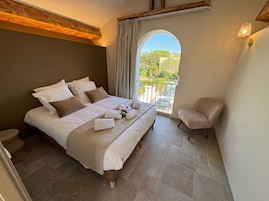 Un dormitorio con una cama grande, una silla y vistas al exterior.