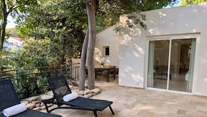A patio with two lounge chairs, a table with breakfast items, and a building with a glass door.