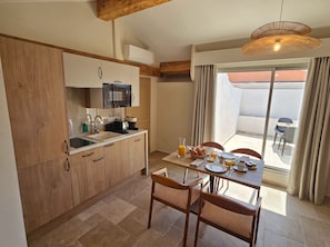 A kitchen with wooden cabinets, a microwave, and a dining area with a table set for breakfast. - Villa Onyra (Saint-Cyr-sur-Mer)