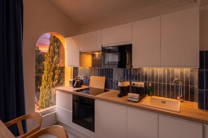 Une cuisine moderne équipée d’un four encastré, d’un évier et d’une fenêtre donnant sur un arbre.