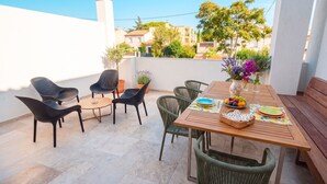 Un patio exterior con una mesa de madera preparada para comer, rodeado de sillas de mimbre.
