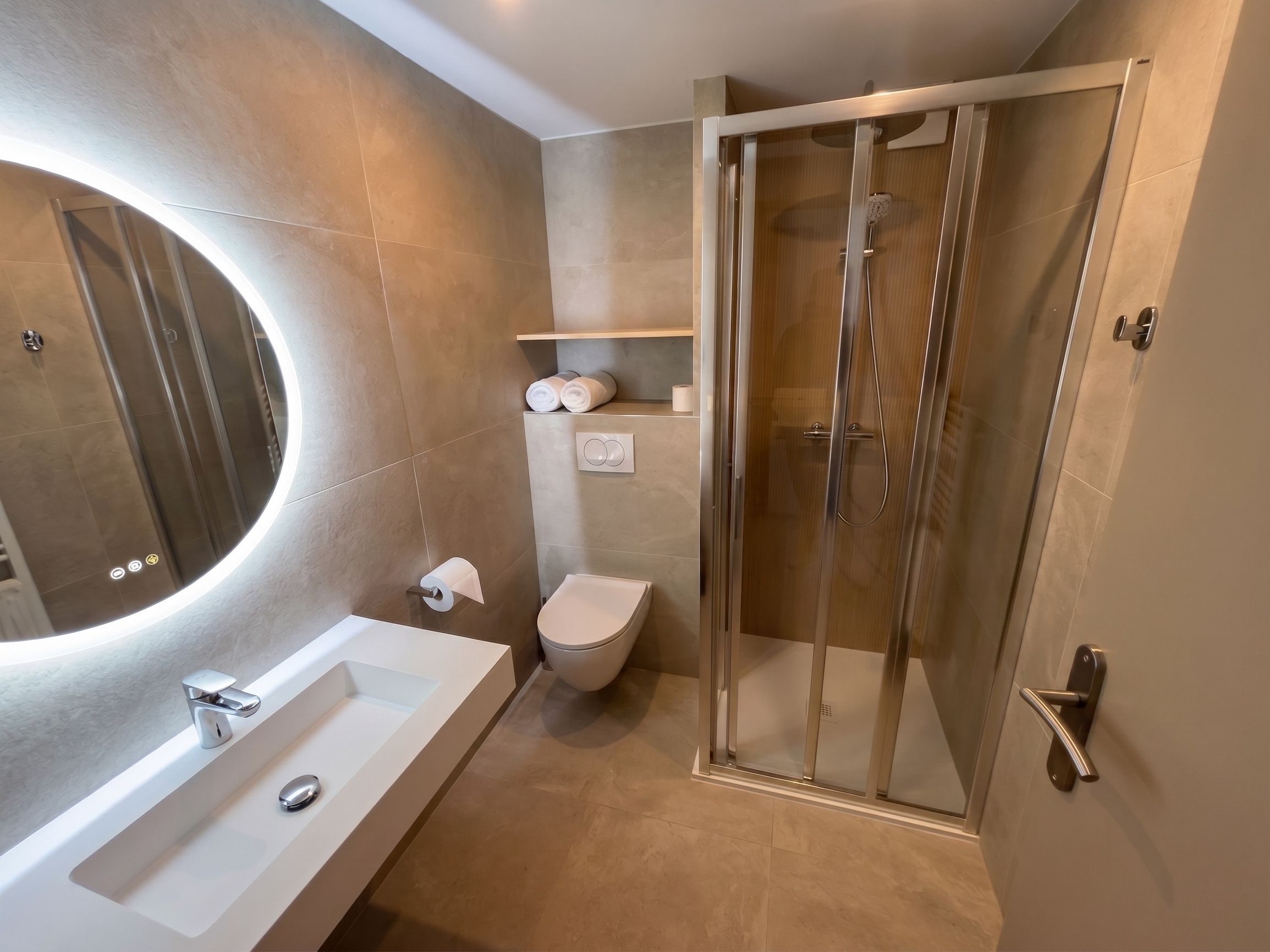 A modern bathroom with a glass-enclosed shower, a white sink, and a toilet.