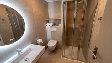 A modern bathroom with a glass-enclosed shower, a white sink, and a toilet.