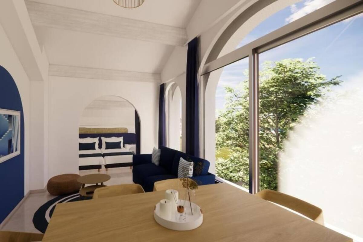 A modern room with a wooden dining table, blue walls, and a large window with a view of trees.