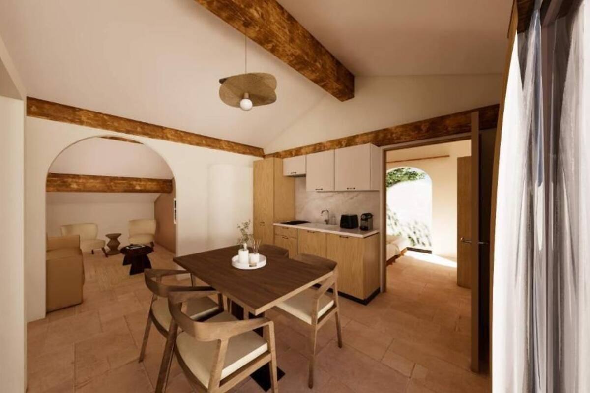 A spacious living area with a wooden dining table, a sofa, and a kitchen in the background.