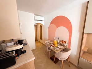 A modern kitchen with a dining area, featuring a breakfast setup with croissants, orange juice, and a vase of lavender. - Villa Onyra (Saint-Cyr-sur-Mer)