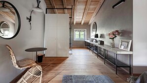 Une cuisine moderne avec des poutres en bois, un coin repas avec une table et des chaises, et une vue sur l’extérieur.