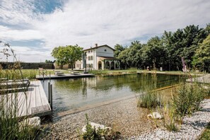 Ein Haus mit Teich, Steg und umgebender Bepflanzung.