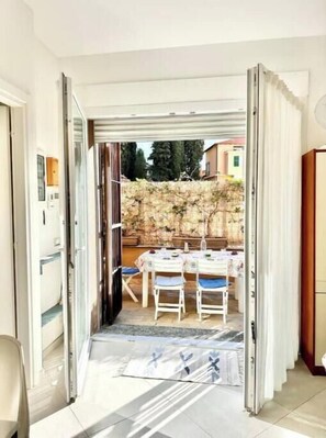 Una habitación con puerta corrediza de vidrio que da a un espacio exterior con mesa y sillas.