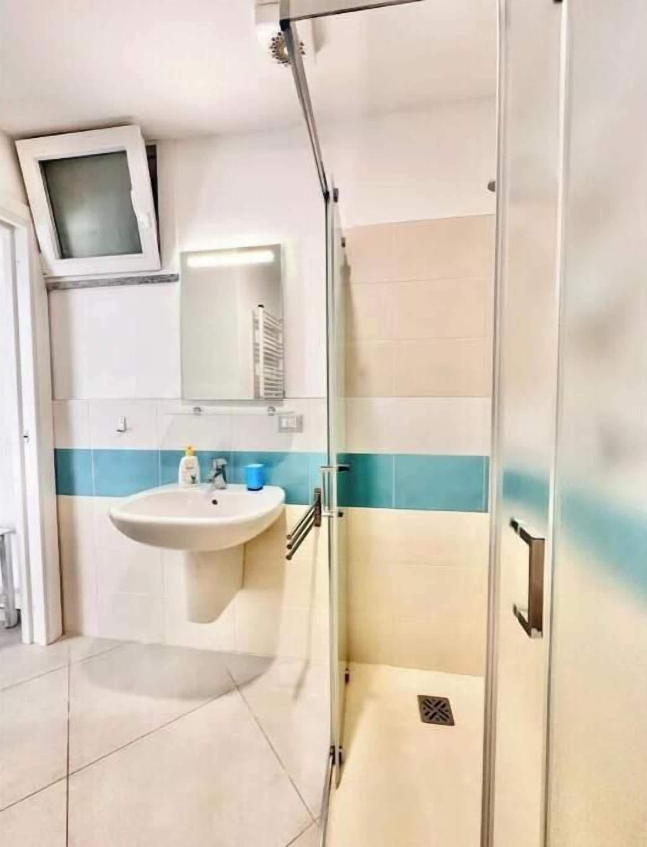 Un baño con lavabo, espejo y ducha.