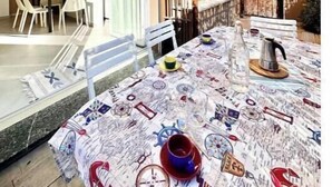 Un espacio de comedor al aire libre con una mesa preparada para dos, una silla y vistas del interior del edificio.