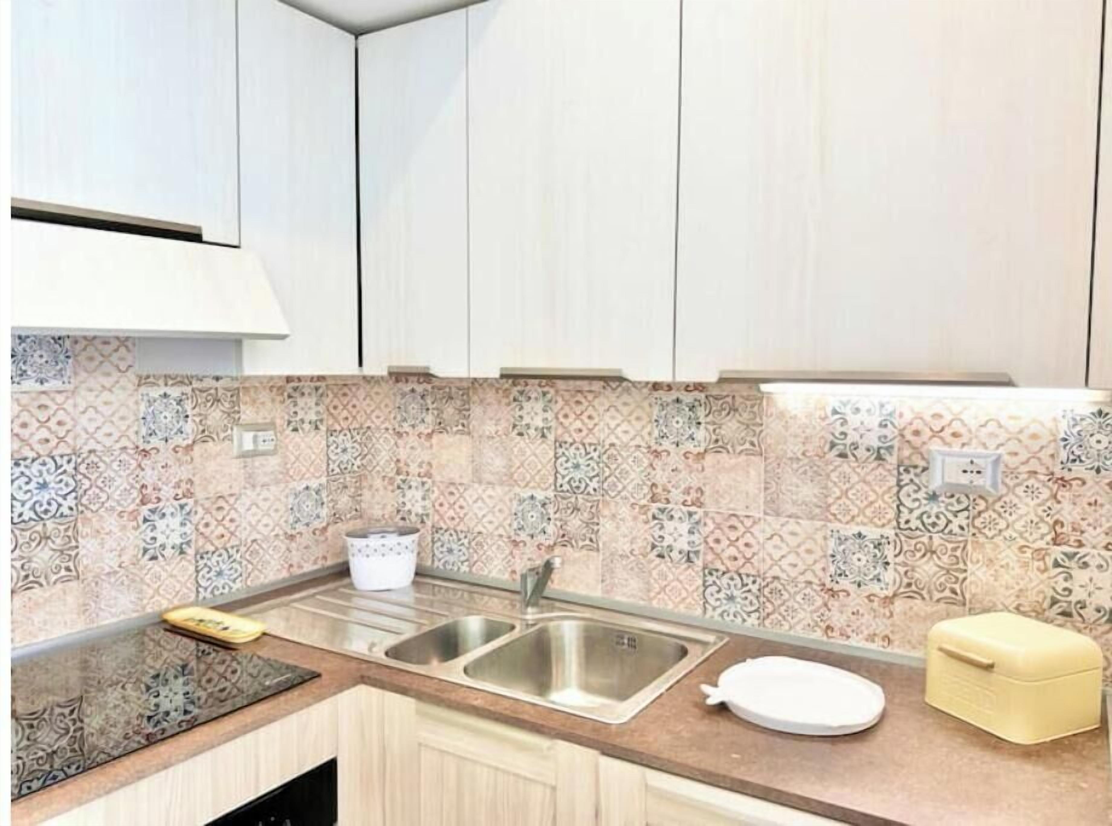 Una cucina con lavello, piano di lavoro e schienale decorato.