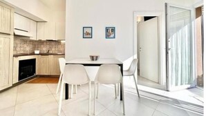 Una cocina moderna con armarios blancos, una mesa de comedor con cuatro sillas y dos cuadros en la pared.