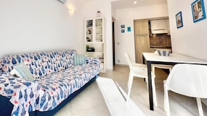 Una sala moderna con un sofá, una mesa de comedor y una zona de cocina.