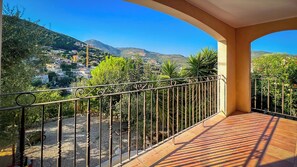 Ein Balkon mit Blick auf ein Hügeldorf, einem Metallgeländer und einem Fliesenboden.