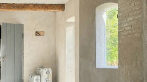 Een kamer met een houten plafond, een raam met uitzicht op groen en een deur.