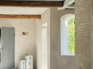 Ein Zimmer mit Holzbalkendecke, einem Fenster mit Blick auf Grünflächen und einer Tür.