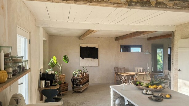 Een landelijke keuken met houten balken, een eethoek met een tafel en stoelen, en een raam met uitzicht.