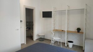 A bedroom with a bed, a desk, a chair, a TV, and a wardrobe. - MARINA BLU ROOMS (Castellammare del Golfo)