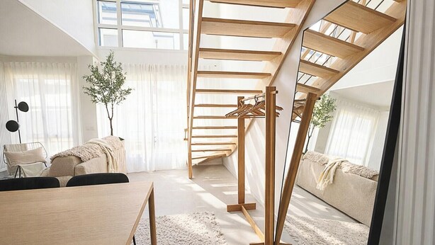 Ein modernes Schlafzimmer im Loft-Stil mit schrägen Wänden, einer eingebauten Holztreppe, einem Essbereich und einem großen Fenster.