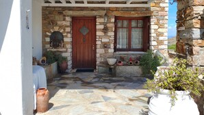 A stone building with a wooden door, a window with curtains, and a stone wall with a welcome sign. - Sun Holiday Kea Private Pool Sea View (Kea)