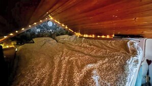 A bedroom with a bed, wooden ceiling, and string lights. - Lakeside cabin with paddle board (Lerum)