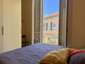 Une chambre à coucher avec un lit, une chaise et une fenêtre donnant sur un immeuble.