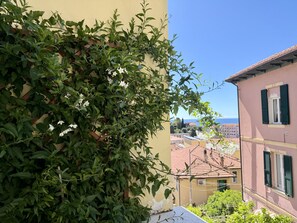 Un balcon agrémenté d’un feuillage verdoyant et offrant une vue sur une ville côtière.