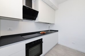Eine moderne Küche mit weißen Schränken, einer schwarzen Arbeitsplatte, einem eingebauten Backofen und einer Mikrowelle.