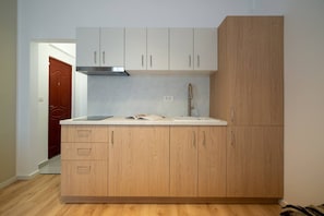 Eine kompakte Küche mit weißen Schränken, einer Edelstahl-Dunstabzugshaube und einem Holzboden.