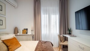 Et moderne soveværelse med seng, natbord og skrivebord med stol.