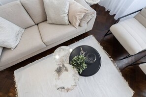 A living room with a sofa, a coffee table with a plant, and a chair. - Luxury 2-Room Apartment | Central (Bucharest)