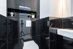 A modern bathroom with a glass shower enclosure, a white sink, and a tripod-mounted camera. - Luxury 2-Room Apartment | Central (Bucharest)